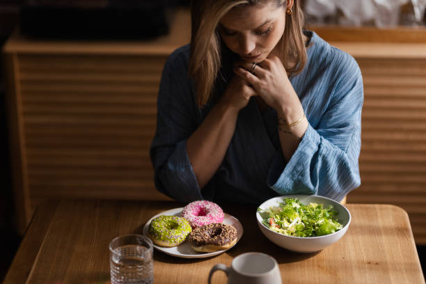 istock Young woman having diet, deciding between salad and donuts. 1524484942