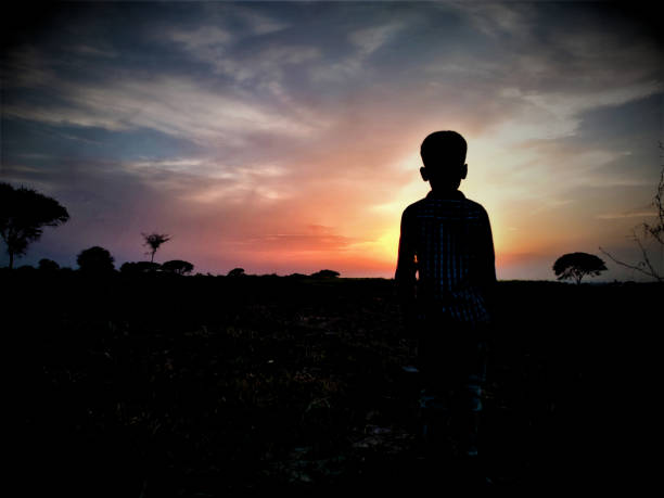 A village child is watching pretty sunset.