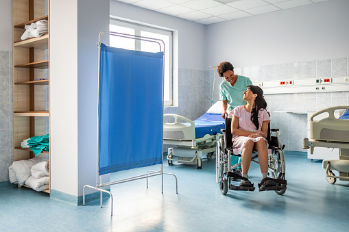 Woman in wheelchair with nurse in hospital