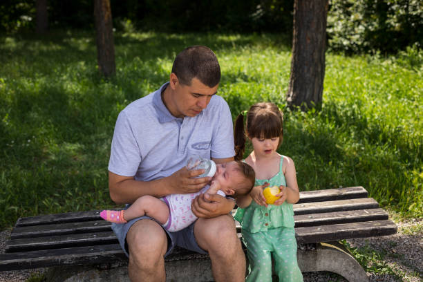 istock Father is feeding the children while sitting on a public bench. 1524557639