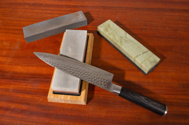 istock Craftsman sharpening knives on a Japanese whetstone, on a wooden table 1524593120