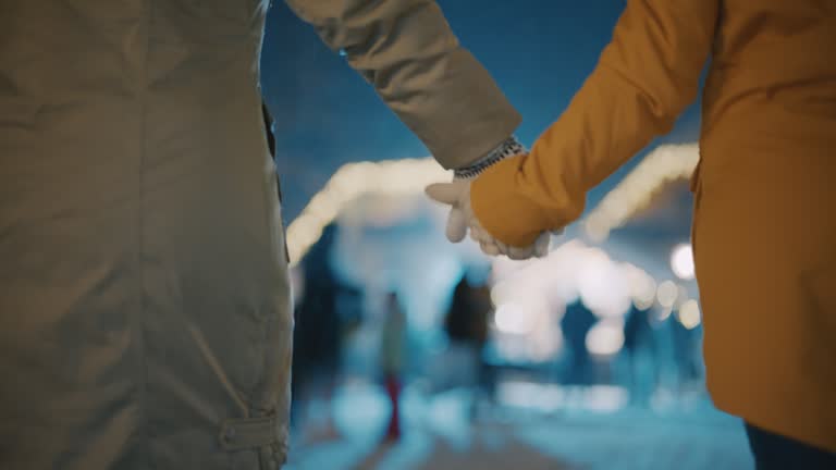 SLO MO Unrecognizable couple holds hands while walking through a Christmas market