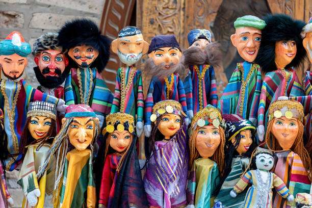 Dolls dressed in traditional uzbek costumes. Traditional souvenir puppet from painted mashed paper (papier mache). Itchan Kala (Xiva Ichon Qala). Souvenir and gift concept. April 10, 2023. Khiva, Uzbekistan.