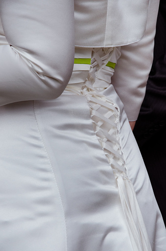 Close-up of a lace black belt on a beige dress. Romantic beige lace dress with black lace belt on a tailor's mannequin. Women's clothing in a seamstress's workshop.