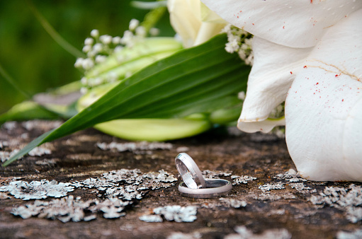 Close up of two silver wedding rings and beautiful flower bouquet