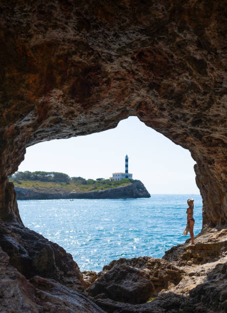 istock Woman inside cave, view Lighthouse Portocolom in Mallorca. 1524758442