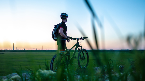Cyclist on green meadows on a summer evening under sunset. Fitness concept.