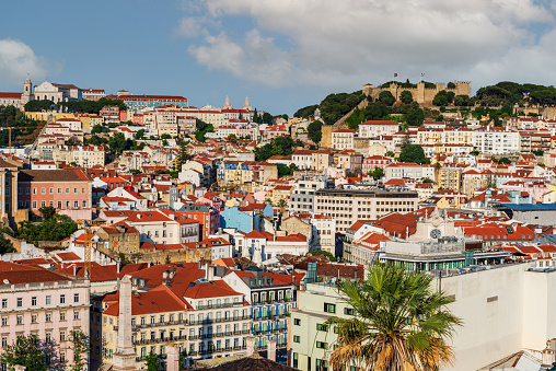Alfama neighborhood with old buildings in Lisbon with the castle of Saint George on top of the hill.