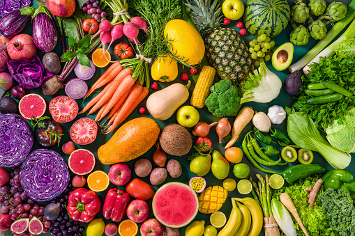 Colorful raw fruits and vegetables varied vegan food, vivid rainbow arrangement