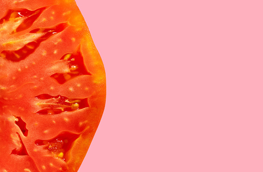 Fresh tomato half cut macro closeup texture detail mediterranean food with pink copy space