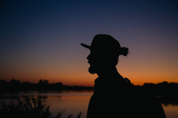istock A bearded man with backpack and with cap at sunset near the lake. 1524883864