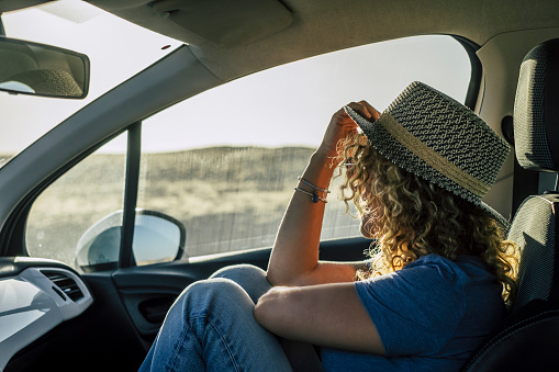 One woman sitting inside passenger car interior looking beautiful outside country side. Concept of travel people and transport. Free female in summer road trip adventure. Wanderlust and destination