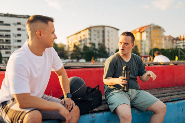 istock A man with a chromosomal disorder known as Down's syndrome is casually chatting with his best friend as he sits on a bench in a sports field 1524920981