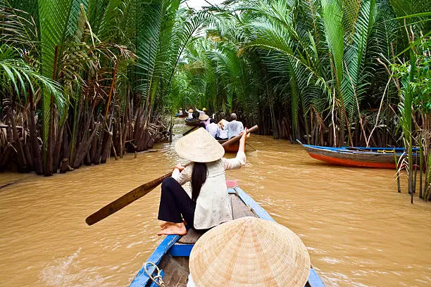 Vietnamese woman rowing a boat in Mekong River in Vietnam