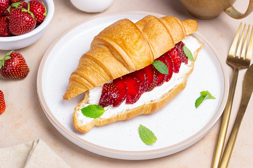 Croissant with strawberries, white cheese and mint. Breakfast. Vegetarian food
