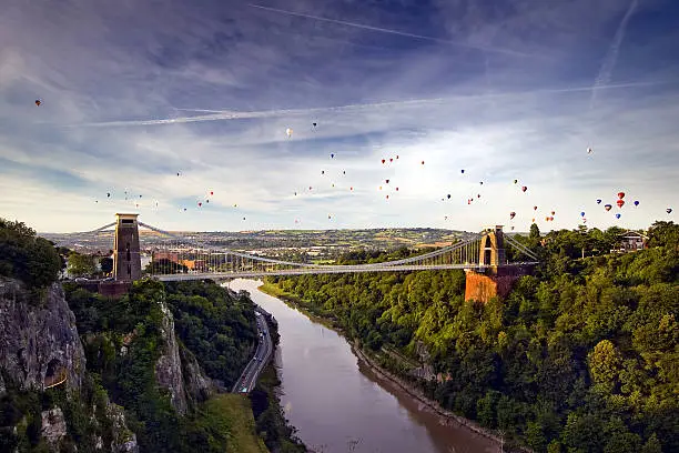 A view up the Avon Gorge of the Clifton Suspension Bridge with a hot air balloon launch behind.