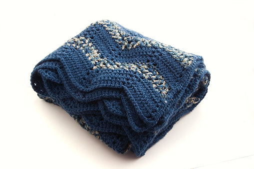 A folded crocheted blanket, isolated on a white background.