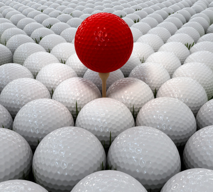 Red golf ball on wood tee over a group of white golf balls.