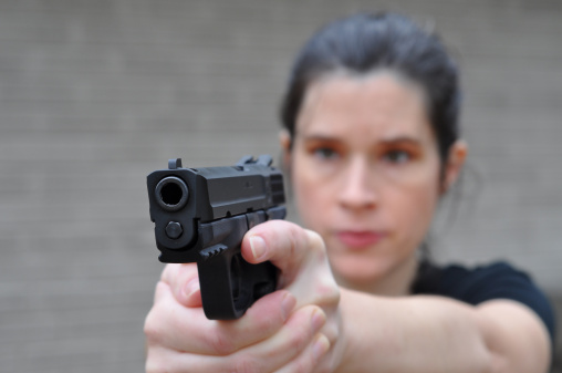 This young woman takes aim with her pistol and is ready to defend herself.