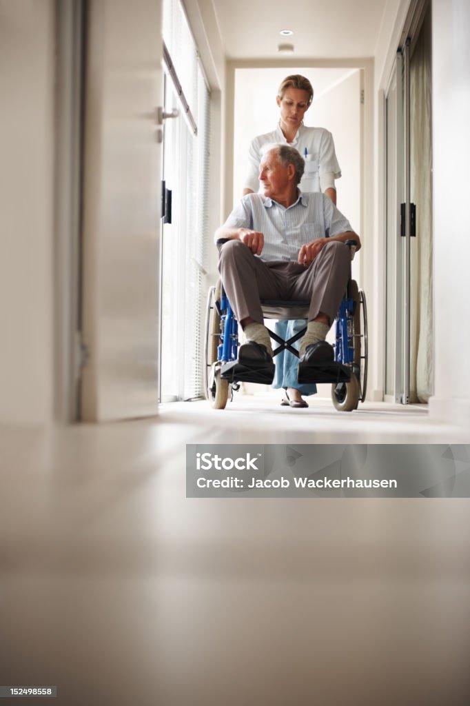 Enfermera empujando un viejo hombre en una silla de ruedas - Foto de stock de Empujar libre de derechos