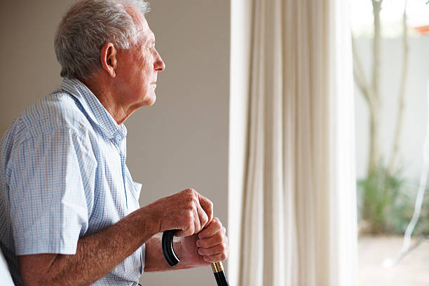 istock Elderly man holding a walking stick looking outside 152498600