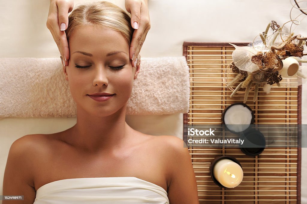 attractive female getting recreation massage of head High angle portrait of an attractive female getting recreation massage of head Facial Massage Stock Photo