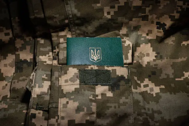 Ukrainian military ID on the background of pixel camouflage uniforms.