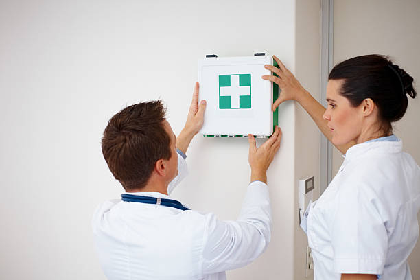 Doctors putting first aid kit on the wall Doctors putting first aid kit on the wall first aid kit wall stock pictures, royalty-free photos & images
