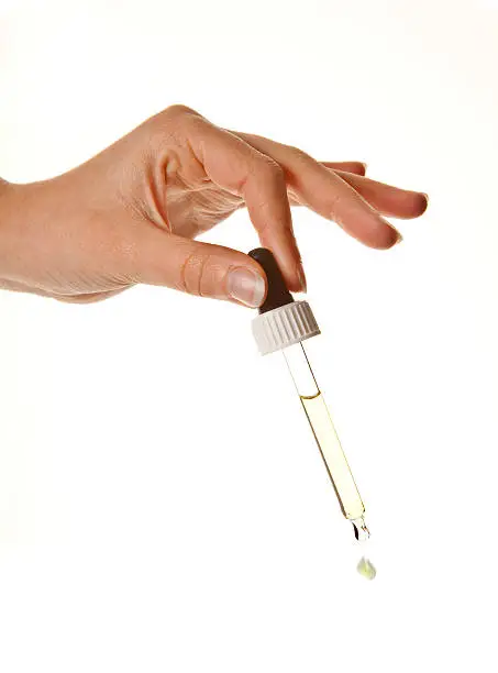 Hands of a woman holding an eyerdropper with fluid