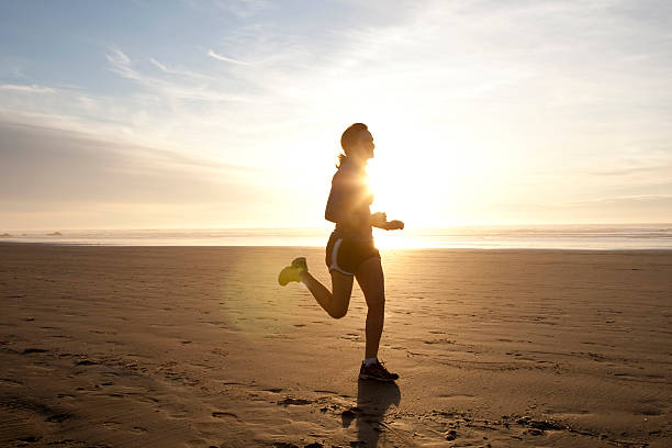 A female jogging towards the sunset stock photo