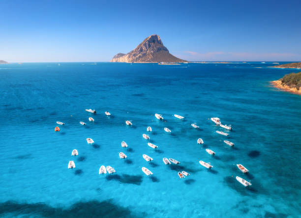 vista aérea de lanchas a motor en el mar azul al atardecer en verano. cerdeña, italia. paisaje marino tropical con lanchas rápidas, yates, laguna marina, montaña, agua azul transparente, cielo. vista superior del océano con drones - above the cloud sea fotografías e imágenes de stock