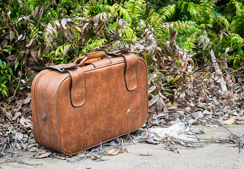 Leather suitcase on rural road. Vintage style. Close up.