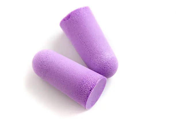 Two purple earplugs, isolated on a white background.