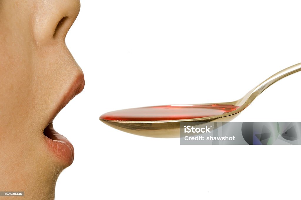 Child takes a spoonful of medicine A child takes a spoonful of medicine. Profile View Stock Photo