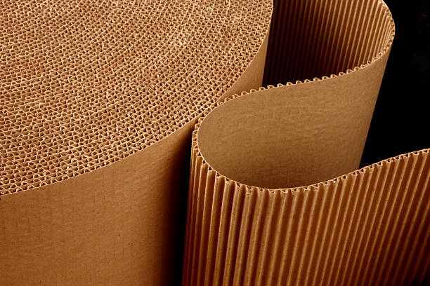 Roll of wavy corrugated close up shot of corrugated packing material uncurling on black background rolled up photos stock pictures, royalty-free photos & images