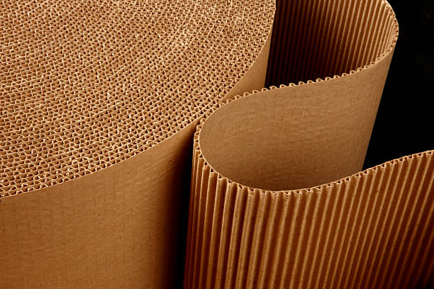 Roll of wavy corrugated close up shot of corrugated packing material uncurling on black background corrogated board stock pictures, royalty-free photos & images