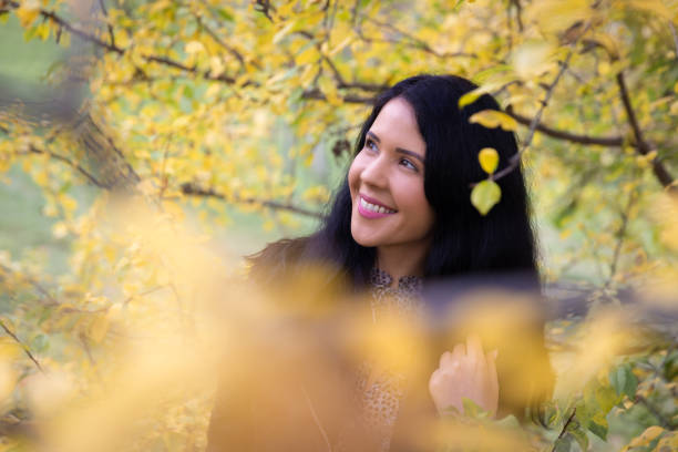 Beautiful smiling woman outdoor portrait holding a leaf in front of the camera.