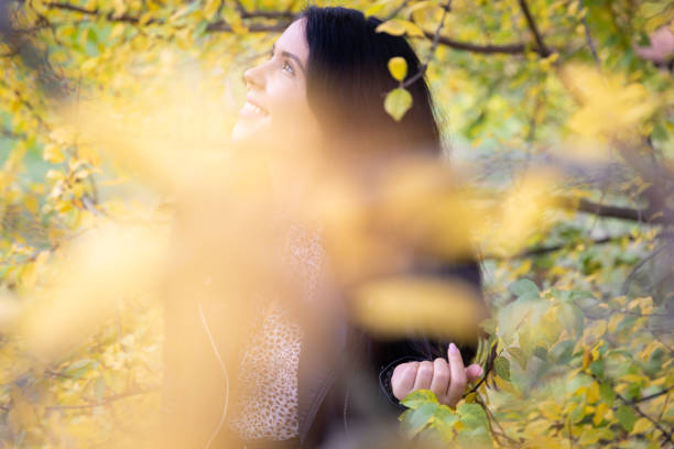 Beautiful smiling woman outdoor portrait holding a leaf in front of the camera.