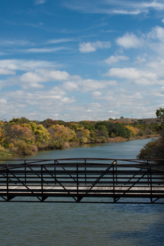A vertical photograph of a footbridge over a river at Quartz Mountain State Park in Oklahoma