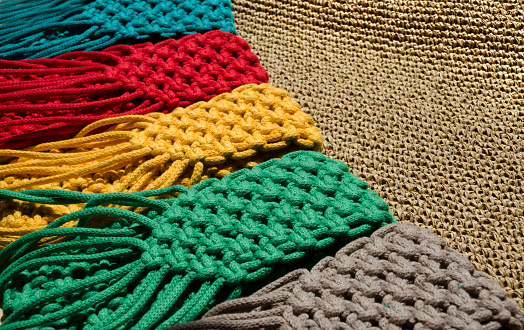 Small handbags knitted with macrame technique. Multicolored mobile phone bags on a wooden background.