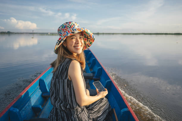 Happy woman enjoying while day dreaming during summer day in a boat on a lake. Copy space.