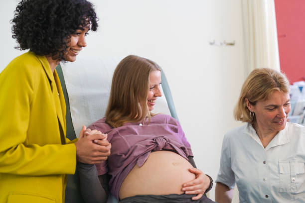 istock A LGBT couple during a check-up visit to their gynecologist after undergoing artificial insemination. The young women sit together, expressing happiness and excitement, in the doctor's office. 1525267042