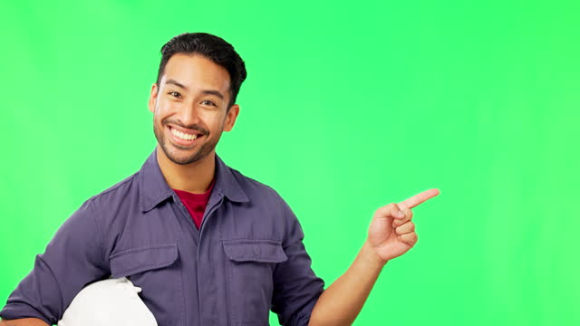 Asian man, engineer and pointing on green screen for product placement or marketing against a studio background. Portrait of happy male contractor showing gesture or point to advertisement on mockup