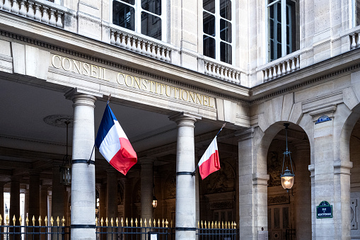 Paris, France - August 21, 2018: French and European flags standing at the entrance of the saving account bank in Paris, France
