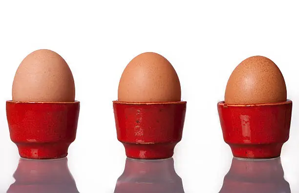 Three Eggs in red Eggcups against a white background