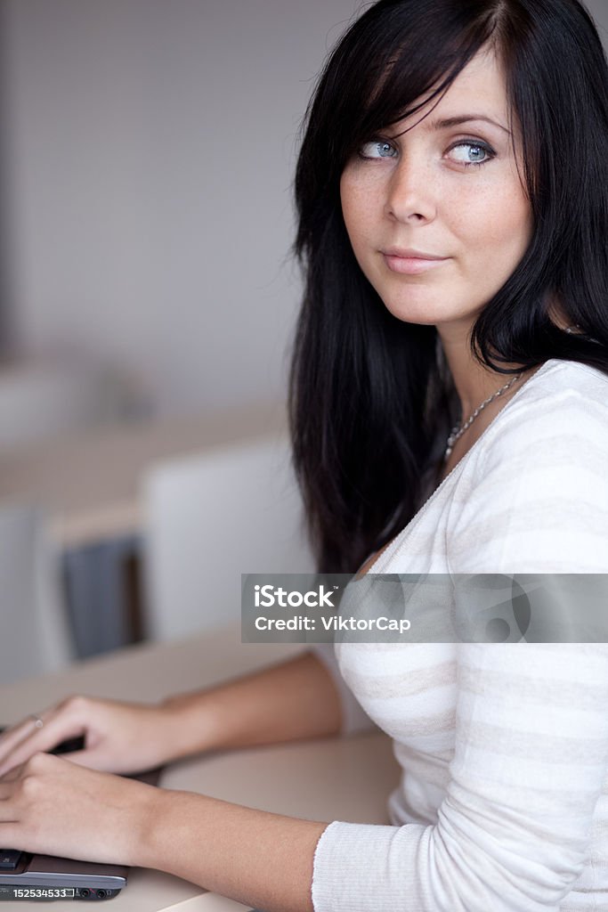 daydreaming pretty young brunette  daydreaming while working/typing on a laptop computer in a office/classroom Adult Stock Photo