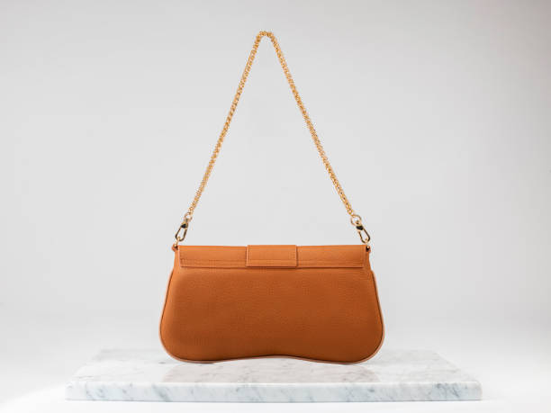 高級レディースバッグ。白い背景に高級オレンジレザーハンドバッグ、大理石の床