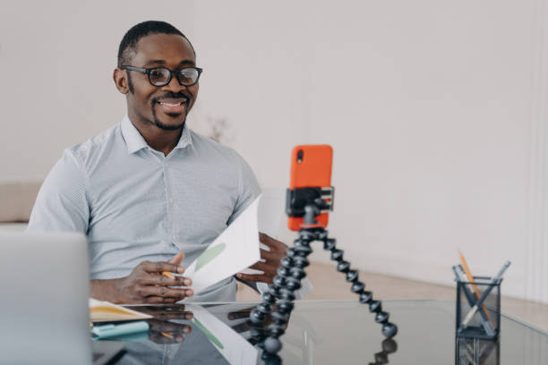 homme d’affaires noir: appel vidéo, smartphone. un coach souriant consulte les clients. - working smiling equipment car photos et images de collection