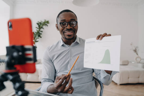 istock Analyst presents stats, online conference via video call. Coach records educational webinar, shows chart on phone. 1525360514