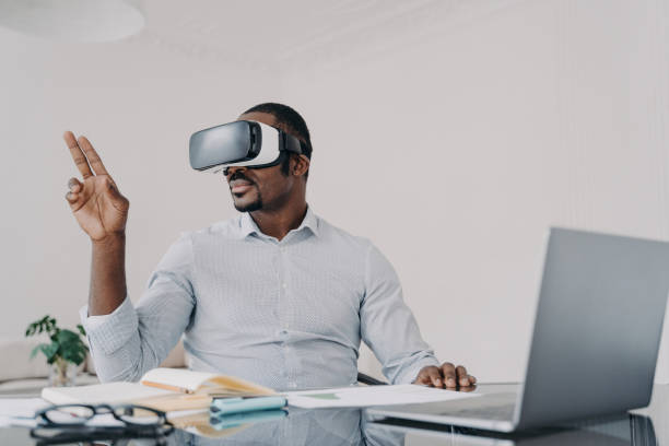 istock Black businessman: VR glasses, cyberspace work on laptop. Manager uses high-tech gadget, augmented reality, business. 1525360519